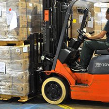 A man driving a forklift in a warehouse.