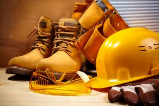 A pair of work boots and hard hat on top of a table.