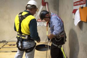 Two men in safety harnesses and a harness are working on the wall.
