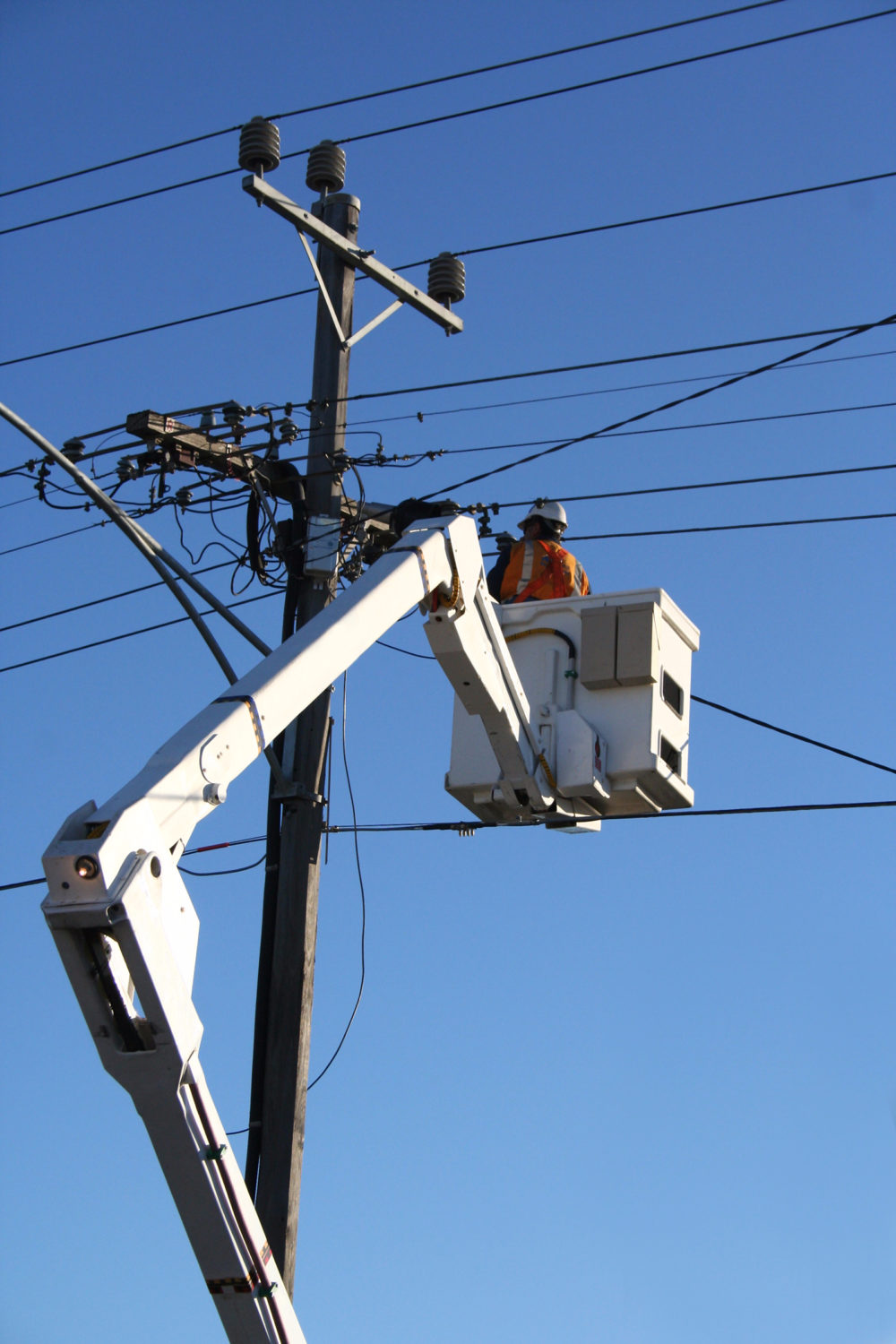 A man in an aerial lift working on power lines.