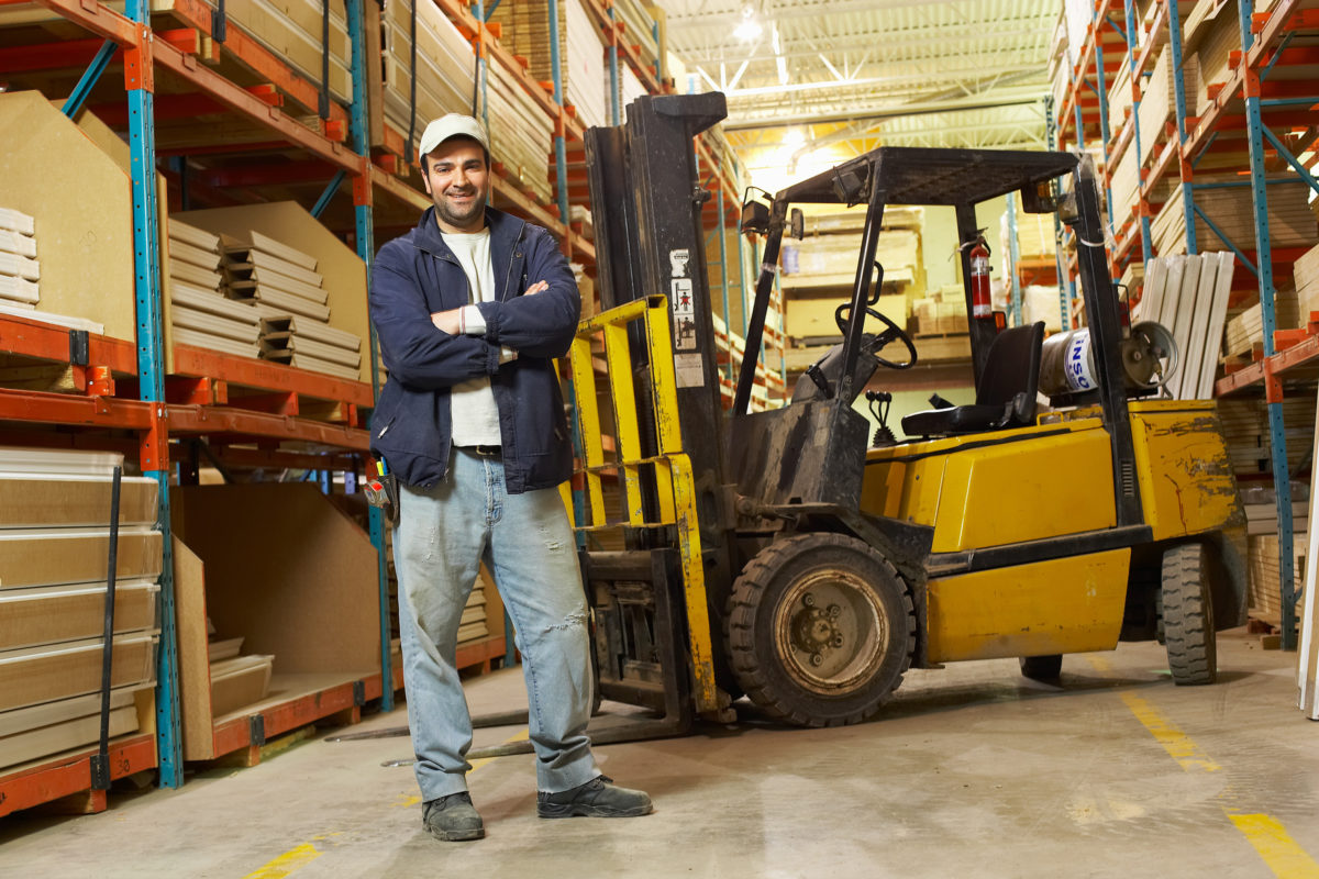 A man standing in front of a yellow forklift.