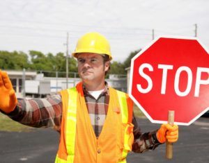 A man holding a stop sign on the side of a road.