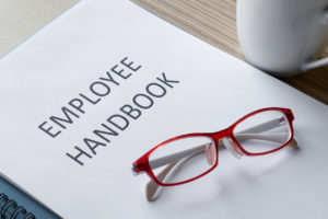 A red eye glasses sitting on top of an employee handbook.
