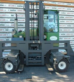 A large green forklift parked in front of a wall.